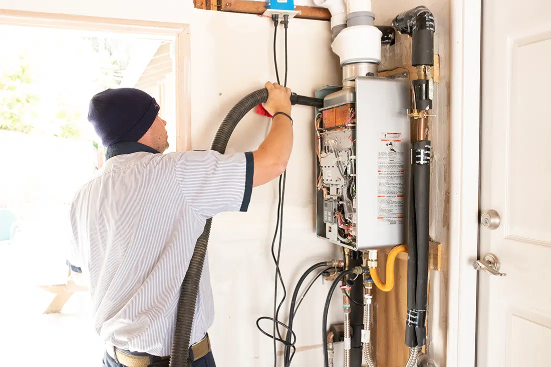 Armstrong Plumbing technician servicing tankless water heater in residential home in Sacramento, CA.
